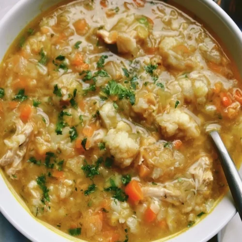 Bowl of anti-inflammatory cauliflower chicken soup with fresh herbs and vegetables.