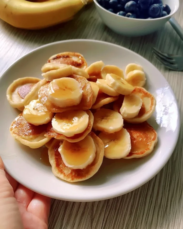 Fluffy banana mini pancakes stacked with fresh bananas and syrup