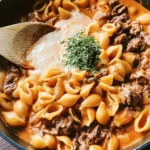 Creamy beef pasta shells served in a bowl, garnished with herbs.