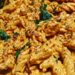 Creamy spicy one-pot buffalo chicken pasta in a bowl with fresh herbs