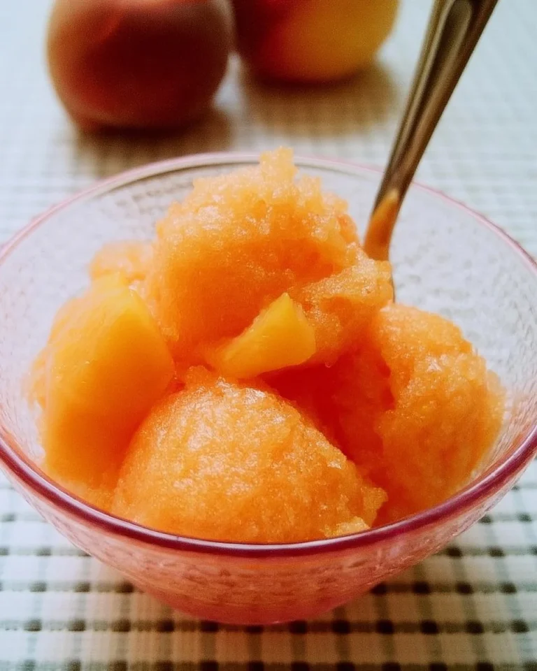 Delicious homemade peach sorbet served in a bowl with a mint leaf.