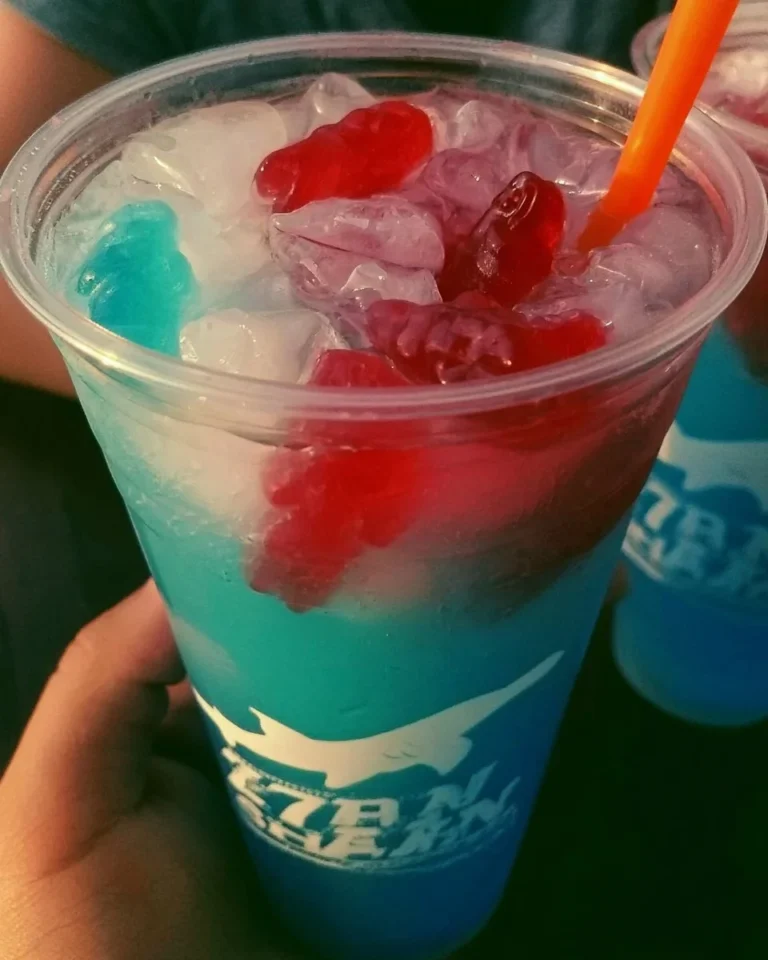 Colorful Gummy Shark Beverage served in a glass with gummy sharks on top.